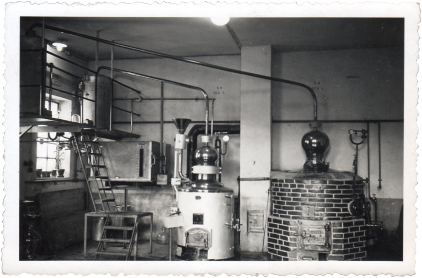 Innenansicht einer traditionellen Brennerei mit Brennkesseln und Leitungen.