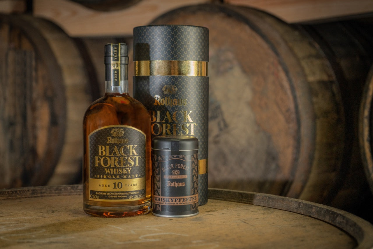 "Rothaus Black Forest Whisky-Flasche mit Verpackung und Pfefferdose auf Fass."