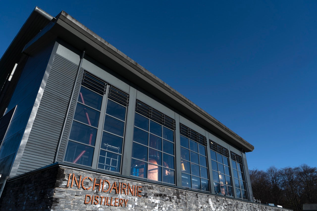 Außenansicht der Inchdairnie Distillery mit modernen Glasfronten unter klarem, blauem Himmel.