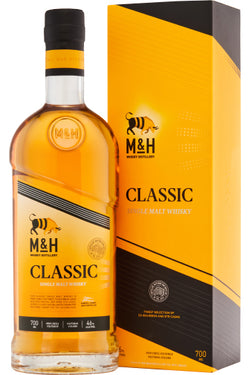Eine Flasche M&H Classic Single Malt Whisky neben der passenden gelben Verpackung.