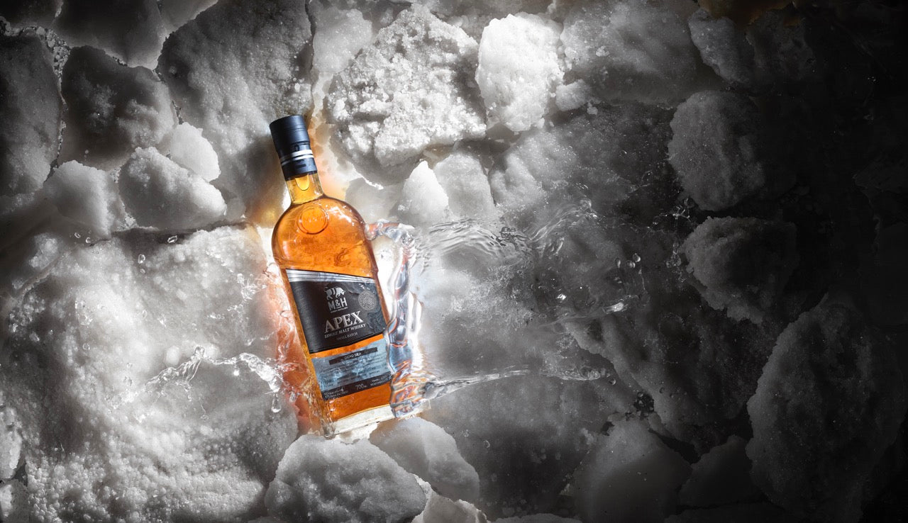 Eine Flasche Whisky liegt umgeben von Eisblöcken.