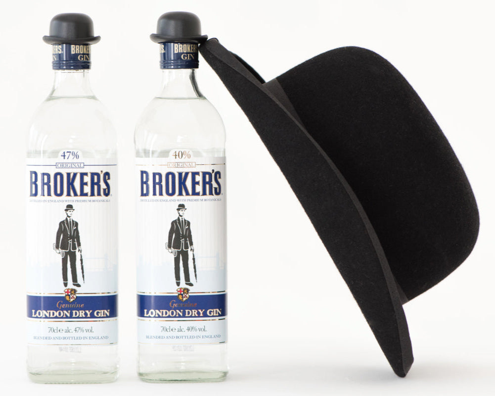 Zwei Flaschen Broker's London Dry Gin mit schwarzen Bowlerhüten auf den Kappen und einem großen Hut daneben.