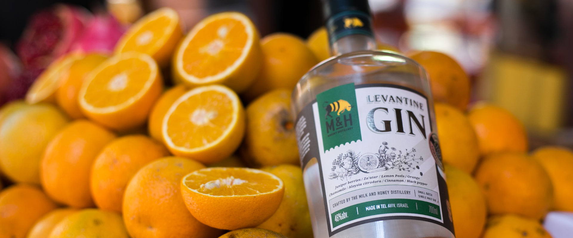 Eine Flasche Levantine Gin liegt auf einem Haufen frischer Orangen, einige davon sind halbiert.