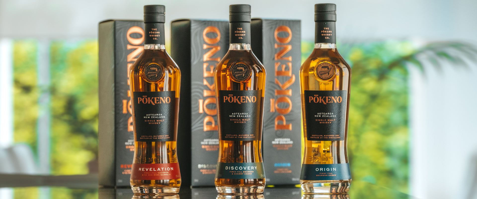Drei Flaschen Pōkeno Single Malt Whisky vor Verpackungen.