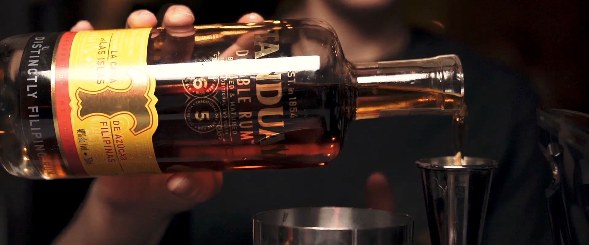 Nahaufnahme einer Rumflasche, aus der eine Person den Inhalt in einen Messbecher gießt.