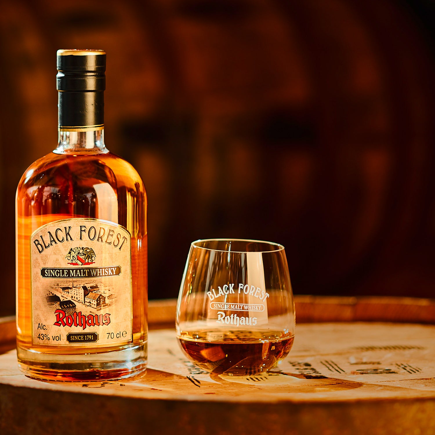 Eine Flasche Black Forest Whisky neben einem Glas auf einem Holztisch.