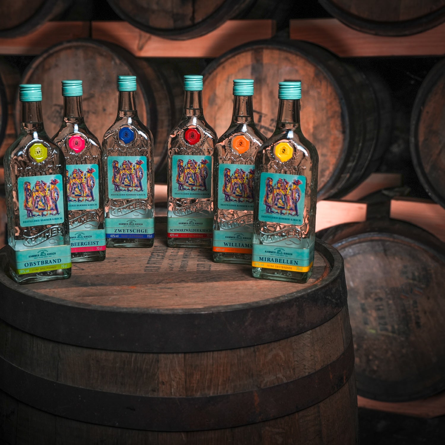 Eine Auswahl von Spirituosenflaschen steht auf einem Holzfass in einem Lager mit weiteren Fässern im Hintergrund.