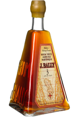 Eine dreieckige Flasche J. Bally Rhum Vieux Agricole Martinique mit einem gelben Etikett und Holzkorken.