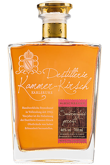 Eine Flasche Kirschbrand der Destillerie Kammer-Kirsch mit bernsteinfarbener Flüssigkeit und goldener Kappe.
